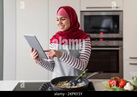 Donna mediorientale in hijab controllo ricetta su Internet Foto Stock