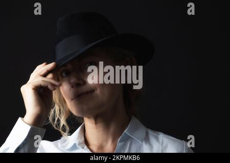 Basso ritratto chiave di donna sorridente di mezza età con cappello nero. Foto Stock