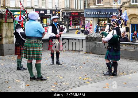 Gli spettatori che guardano i bagpiper in kilt tradizionali che si esibiscono in Hunter Square, appena fuori dal Royal Mile, Edimburgo, Scozia, Regno Unito. Foto Stock