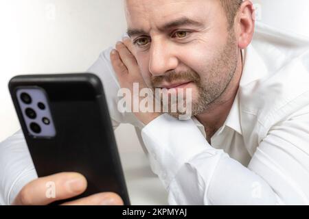 l'uomo caucasico con barba utilizza uno smartphone. foto da studio Foto Stock