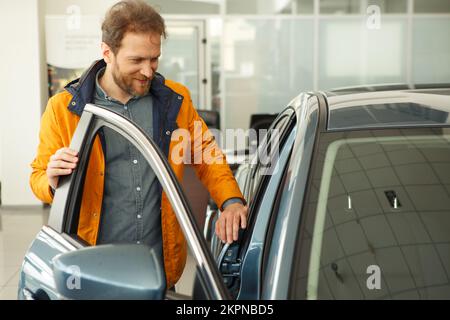 Uomo bello che sceglie l'automobile al centro dell'automobile. Foto Stock