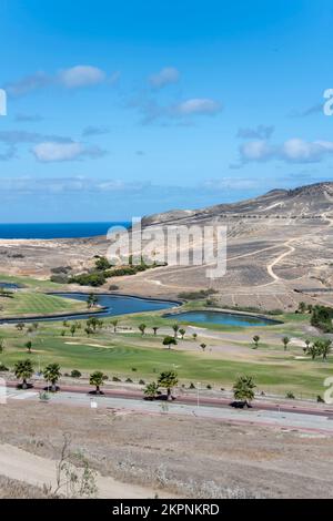 Paesaggio con campo da golf verde tra pendii aridi, girato alla luce di una luminosa caduta sull'isola di Porto Santo, Portogallo Foto Stock