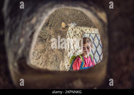 Ragazzo turistico esplorando la valle con formazioni rocciose e grotte delle fate vicino a Goreme in Cappadocia Turchia Foto Stock