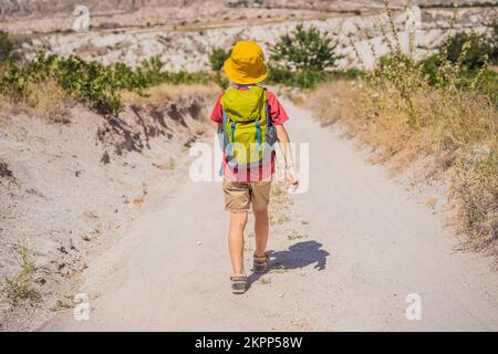 Ragazzo turistico esplorando la valle con formazioni rocciose e grotte delle fate vicino a Goreme in Cappadocia Turchia Foto Stock