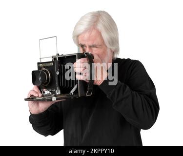 Ripresa orizzontale di un uomo anziano che scatta una fotografia con una fotocamera grafica vintage degli anni 40. Sfondo bianco. Foto Stock