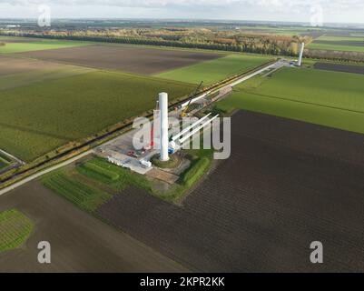 Processo di costruzione di turbine eoliche costruzione di mulini a vento con gru. Parti della turbina eolica, alloggiamento, mozzo, pale in loco. Drone aereo in alto Foto Stock