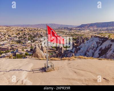 Bandiera turca sulla collina con tipiche formazioni rocciose di tufo della Cappadocia sullo sfondo di un cielo blu, Goreme, Turchia Foto Stock