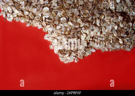 Mucchio di fiocchi di segale d'avena su fondo di colore rosso. Foto Stock