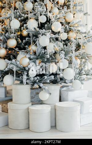 Mucchio di scatole regalo vicino a un bell'albero di Natale al coperto Foto Stock