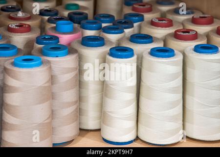 Cucire coni di filo di tonalità diversa di colori su scaffale in studio di cucito closeup Foto Stock
