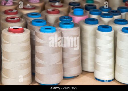 Cucire coni di filo di tonalità diversa di colori su scaffale in studio di cucito closeup Foto Stock