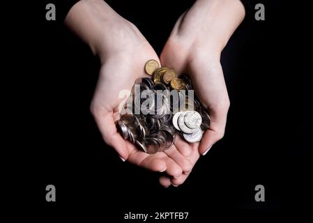 mani che tengono le monete selettive e soft focus isolato su sfondo nero con spazio di copia. anteriore Foto Stock