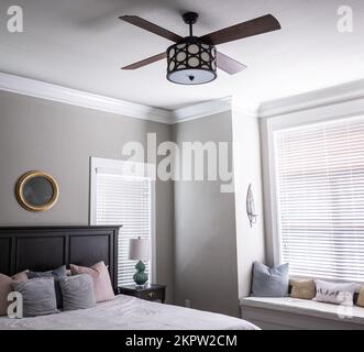 Camera da letto principale grigia luminosa e luminosa con sedile, letto e ventilatore Foto Stock
