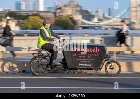 Un corriere assolutamente ciclistico che guida una bicicletta Urban Arrow e-cargo attraverso, London Bridge, Londra, Regno Unito. 17 Ott 2022 Foto Stock