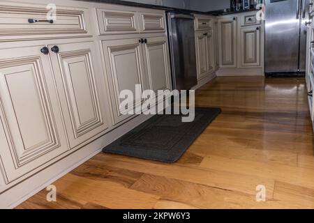 Un basso angolo di vista di rustico crema colroed armadi cucina leggera in una nuova costruzione casa con pavimenti in legno Foto Stock