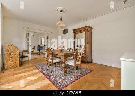 Tavolo e sedie si trovano sotto la lampada luminosa vicino alla pianta in vaso e foto in spaziosa sala da pranzo a casa Foto Stock