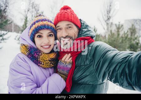 Foto di positivo eccitato moglie marito vestiti cappotti che abbracciano ricoding video vlog all'aperto parco forestale urbano Foto Stock