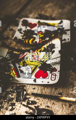Carta da gioco bruciata circondata da ceneri, re e regina di cuori, infelice concetto di amore, rompere nel mazzo Foto Stock