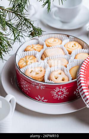 Biscotti danesi al burro in una scatola rossa di lattina di Natale con fiocchi di neve e cervi. Biscotti con torta di tè durante la vacanza. Foto Stock