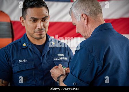 Steven Poulin, vice comandante della Guardia Costiera, spilla una medaglia di commendenza della Guardia Costiera all'uniforme di Petty Officer 2nd Class Jarrett Guerra, compagno di boatswain al Coast Guard Maritime Safety & Security Team Houston, durante un incontro a mani libere al MSST Houston, Texas, 3 novembre 2022. Guerra ha ricevuto una medaglia di commemorazione della Guardia Costiera per aver salvato tre vite sul Rio Grande al confine USA-Messico, il 2 giugno 2022. Foto Stock