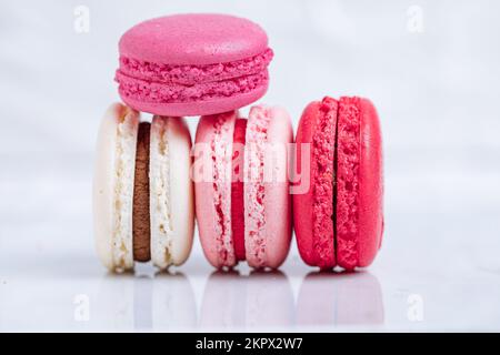 Primo piano di macaron in diversi colori su sfondo bianco luminoso con riflessi sottili sul vassoio in marmo Popolare dessert merengue con farcitura Foto Stock