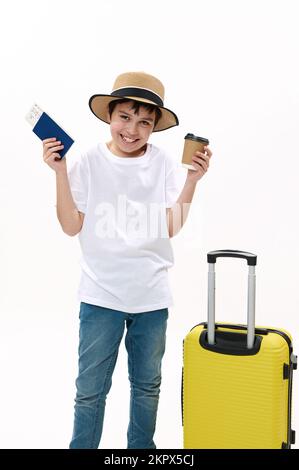 Ragazzo adolescente con valigia, tazza di carta di bevanda calda, carta d'imbarco in attesa di volo, entusiasta di viaggio per le vacanze estive Foto Stock