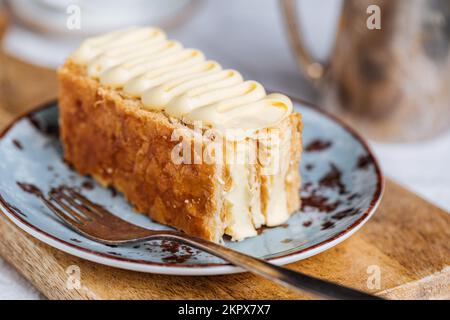 Dessert francese chiamato Mille Feuille o torta Napoleone su rustica tavola di legno. Torta saporita a strati con crema alla vaniglia e pasta sfoglia. Foto Stock