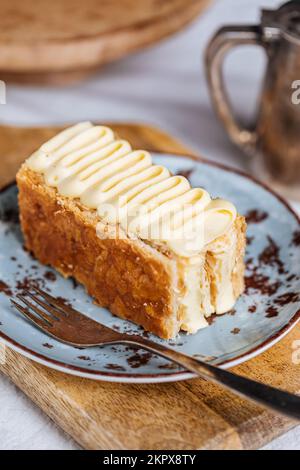 Dessert francese chiamato Mille Feuille o torta Napoleone su rustica tavola di legno. Torta saporita a strati con crema alla vaniglia e pasta sfoglia. Foto Stock