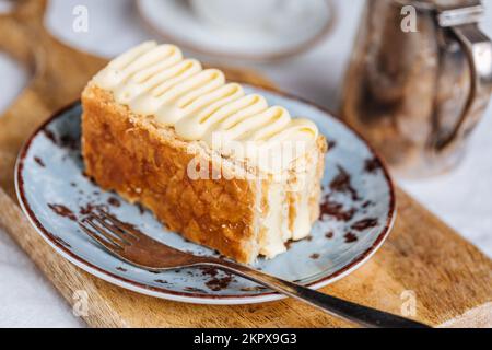 Dessert francese chiamato Mille Feuille o torta Napoleone su rustica tavola di legno. Torta saporita a strati con crema alla vaniglia e pasta sfoglia. Foto Stock