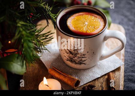 VIN brulé con cannella e arancia servito nella decorazione natalizia su tavola di legno. Festa e Capodanno atmosfera. Albero di Natale in backgrou Foto Stock