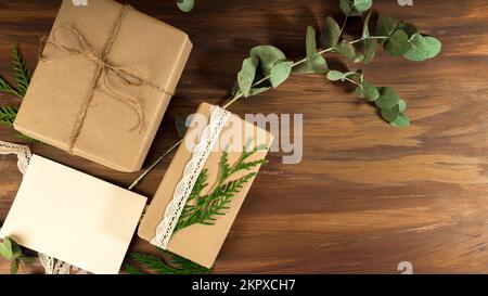 Vista dall'alto di due scatole da regalo confezionate in stile rustico su un tavolo di legno con una cartolina vuota Foto Stock
