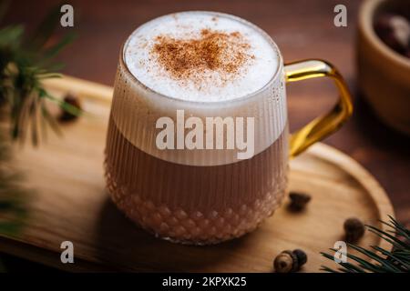 Tazza di vetro di zucca speziata tardi o di melone in un'atmosfera festosa, accogliente e di Natale inverno. Sensazione di umore a casa. Foto Stock