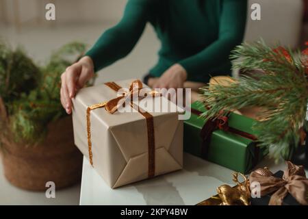 Primo piano di una giovane donna seduta in un salotto che avvolge i regali di Natale Foto Stock