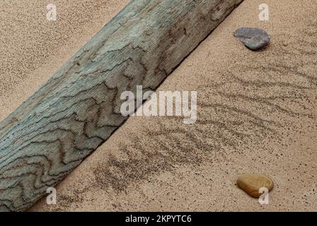 Un pezzo di driftwood, un paio di ciottoli e tessuti di sabbia creano questa scena astratta della spiaggia, Warren Dunes state Park, Berrien County, MI Foto Stock