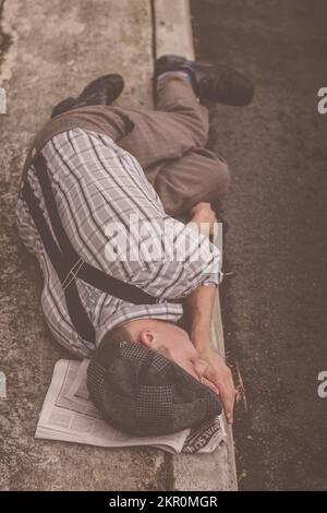 Immagine vintage di un ragazzo di giornale colpito dalla povertà che dormiva sulla sezione dei posti di lavoro durante una crisi di disoccupazione. Nessun licenziamento di lavoro Foto Stock