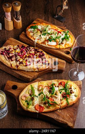 pizze su tavole di legno e un bicchiere di vino rosso Foto Stock