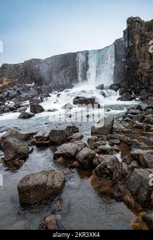 Cascata Öxarárfoss in inverno. La splendida cascata scorre dal fiume Öxará su rocce basaltiche nere nella gola di Almannagjá, Þingvellir Foto Stock