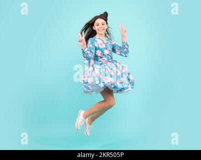 Intera lunghezza overjoyed adolescente ragazza 12 13 14 anni saltando vecchio isolato su sfondo blu studio. Salto divertente. Abito da movimento estivo per bambini. Foto Stock