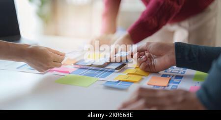 Gruppo di interfacce utente UX o progettisti che lavorano per creare contenuti di applicazioni mobili. Concetto di agenzia di sviluppo digitale creativo Foto Stock