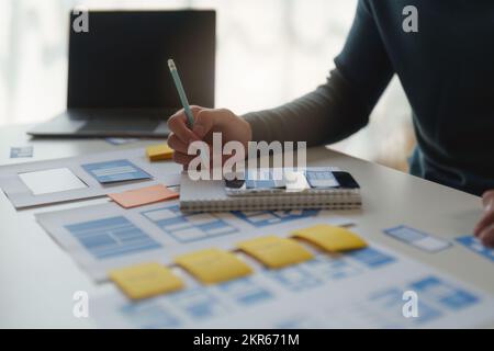 Gruppo di interfacce utente UX o progettisti che lavorano per creare contenuti di applicazioni mobili. Concetto di agenzia di sviluppo digitale creativo Foto Stock