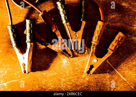 Foto a vita fissa su un set di morsetti per cavi ausiliari su banco rustico in legno per officina Foto Stock