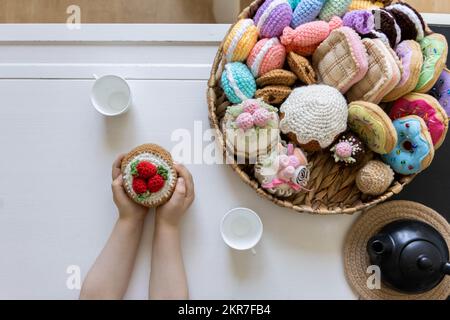 Cibo giocattolo lavorato a maglia da filato. Dolci, dolci, biscotti e torte. Foto Stock