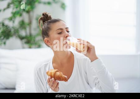 Giovane donna a letto con scatola cibo catering Foto Stock