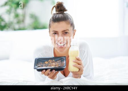 Giovane donna a letto con scatola cibo catering Foto Stock