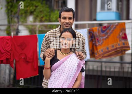 Ritratto di felice giovane coppia in piedi insieme nel cortile Foto Stock
