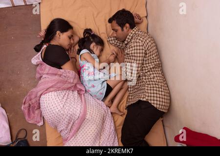 Vista dall'alto della giovane coppia e della loro figlia che dormono insieme sul letto Foto Stock