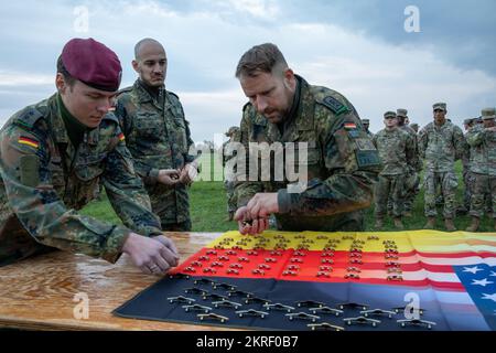 I jumpmasters tedeschi con la Brigata Airborne 26th raccolgono i distintivi paracadutisti tedeschi prima di fissarli in italiano e negli Stati Uniti Paracadutisti dell'esercito dopo aver condotto un'operazione aerea a Juliet Drop zone, Italia, 15 novembre 2022. I paracadutisti hanno tenuto una cerimonia dopo il completamento delle operazioni di salto e hanno scambiato i badge aerei appartenenti al loro paese. La Brigata Airborne 173rd è la U.S.A. Forza di risposta di contingenza dell'esercito in Europa, capace di proiettare le forze pronte dovunque negli Stati Uniti Aree di responsabilità dei comandi europei, africani o centrali. Foto Stock