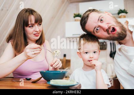 La famiglia è molto felice di mangiare la pasta in cucina Foto Stock