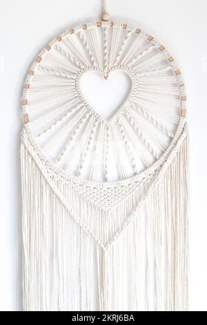 Cuore di macrame bianco intrecciato a mano nell'anello appeso alla parete Foto Stock