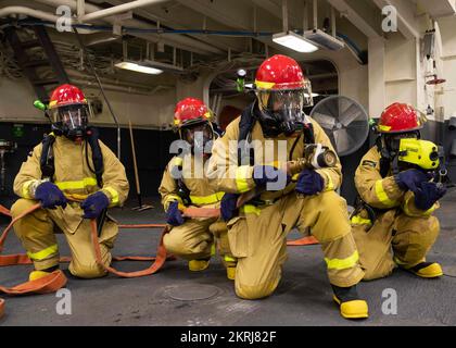 221118-N-TT639-1029 OCEANO PACIFICO (18 novembre 2022) – i marinai combattono un incendio simulato durante un'esercitazione generale nell'area di stivaggio del veicolo a bordo del vettore d'assalto anfibio USS Tripoli (LHA 7) 18 novembre 2022. Tripoli sta conducendo operazioni di routine nella U.S. 3rd Fleet. Foto Stock